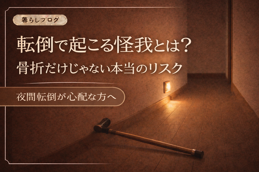 夜の廊下に足元灯が優しく灯り、床に長い杖が倒れている様子。転倒による怪我のリスクをイメージしたサムネイル画像。